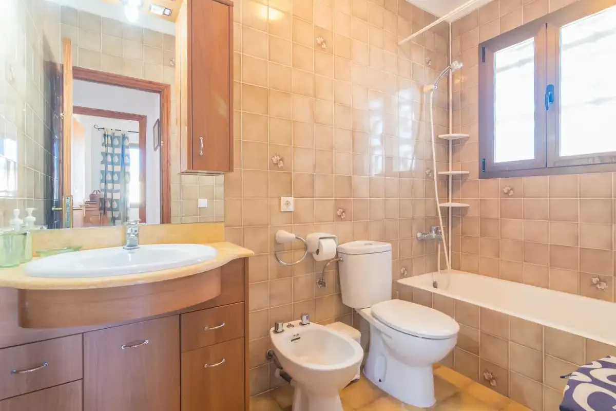 Un baño con azulejos, lavabo, inodoro y bañera.