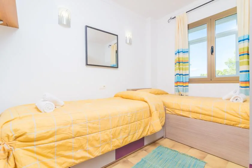 Un dormitorio con dos camas cubiertas con ropa de cama amarilla junto a una ventana.