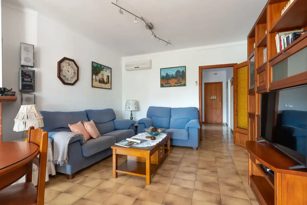 Sala de estar con asientos, una mesa de centro y estanterías de madera.