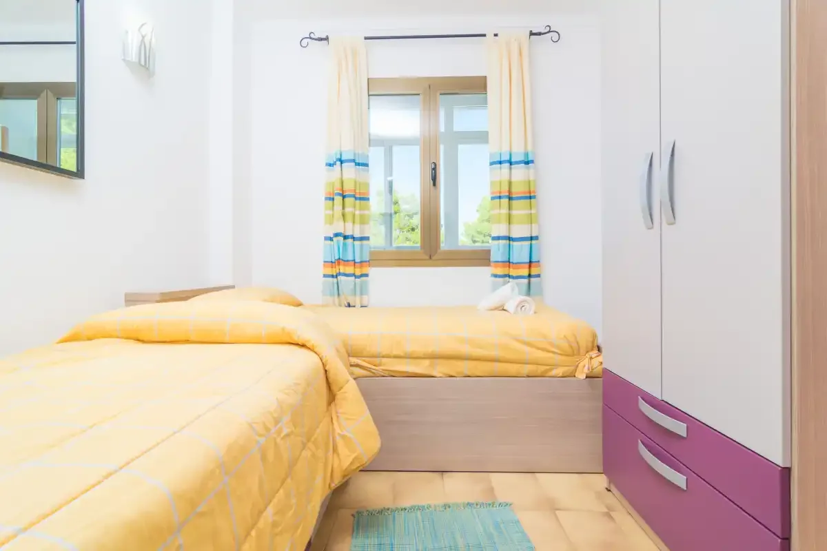 Un dormitorio con ropa de cama amarilla, una ventana y un armario.