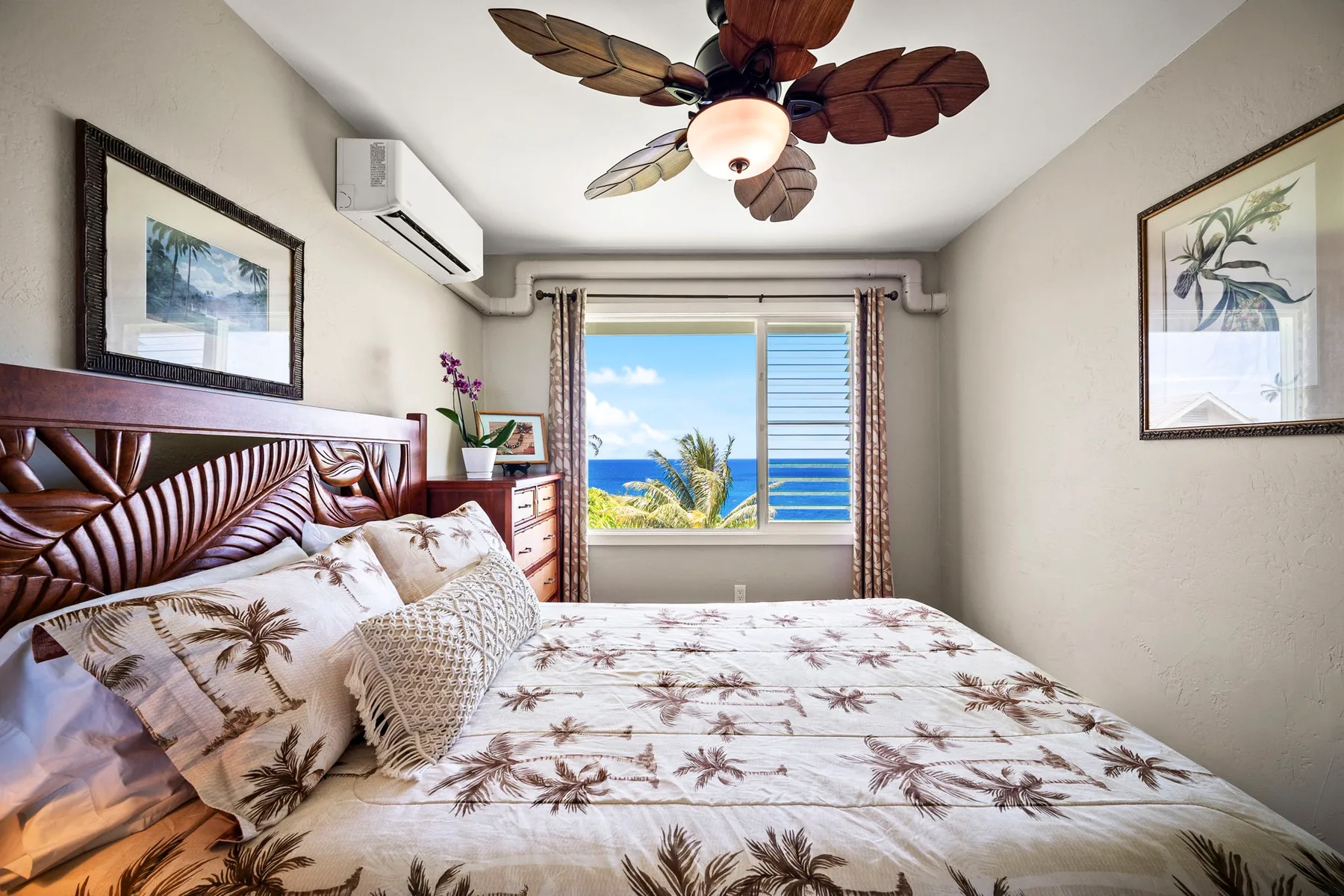 Un dormitorio con una cama estampada y una ventana con vista al océano.