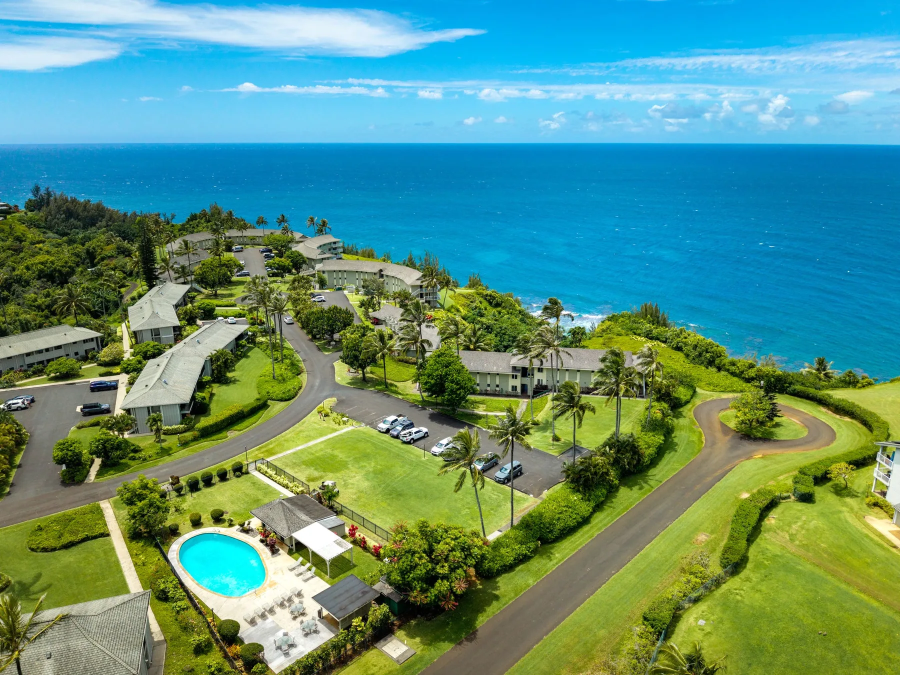Vista aérea de un complejo costero con edificios, jardines y una piscina.