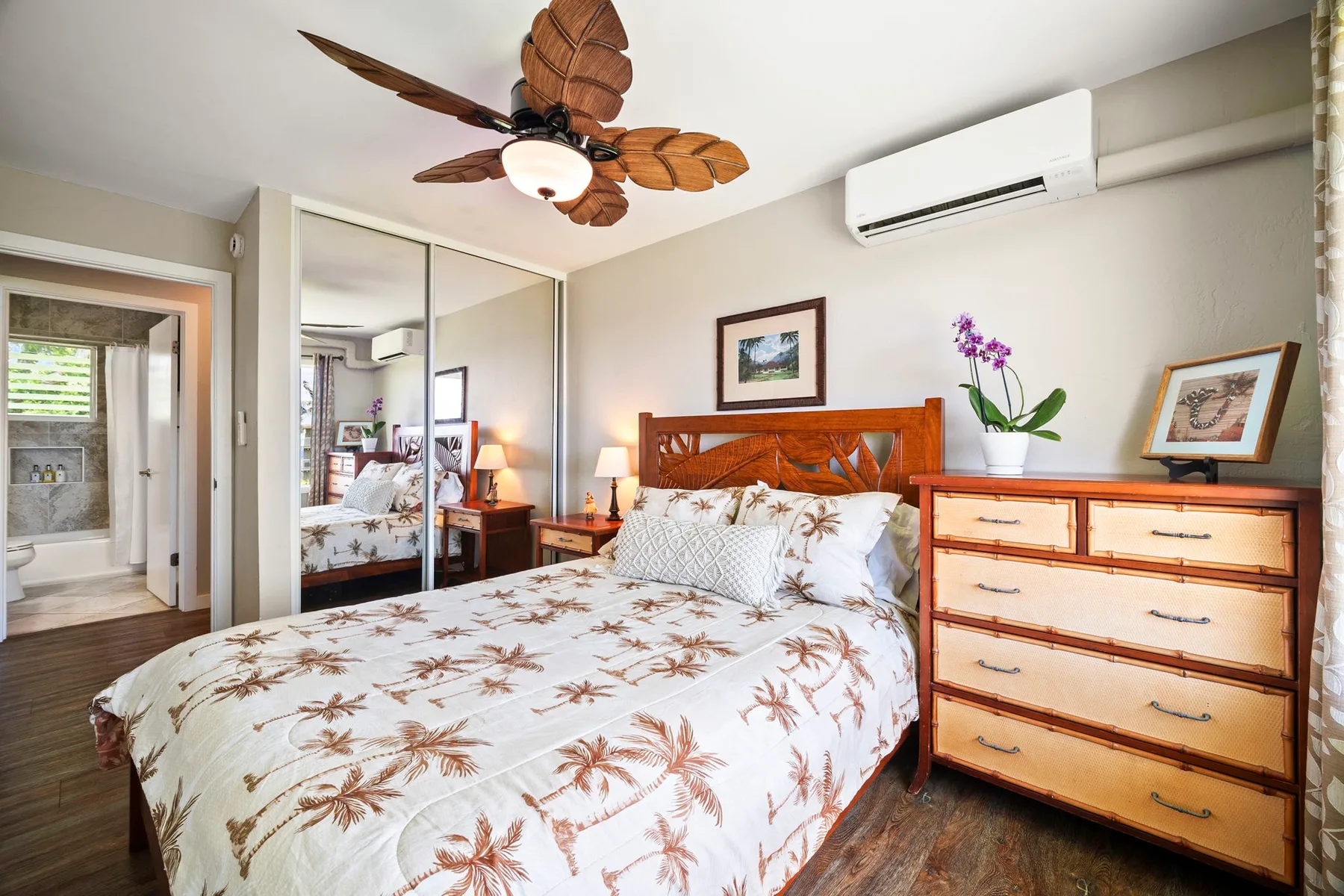 Un dormitorio con una cama, puertas de armario espejadas y una cómoda de madera.