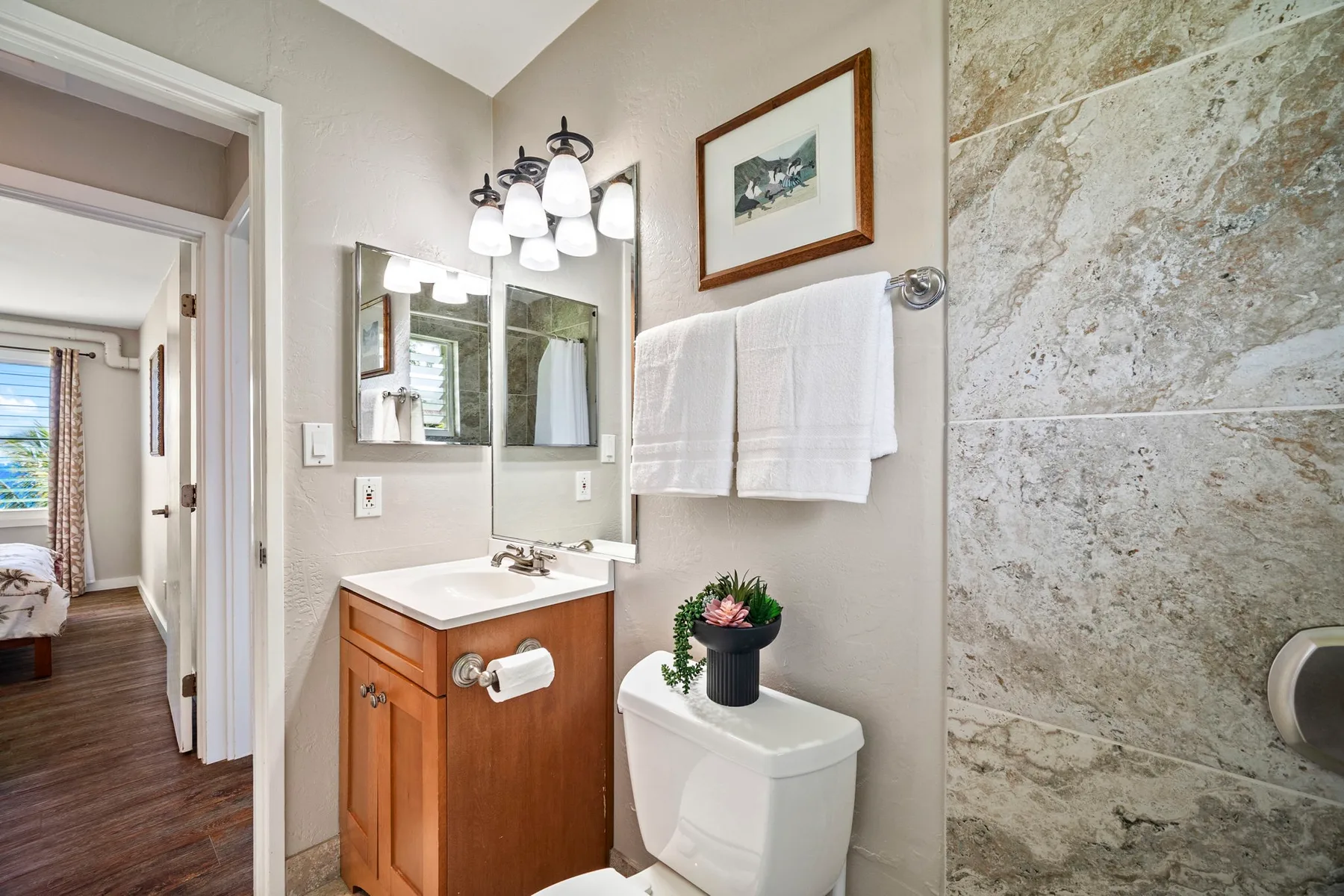 Un baño con lavabo, espejo, inodoro y una pared con diseño de piedra.