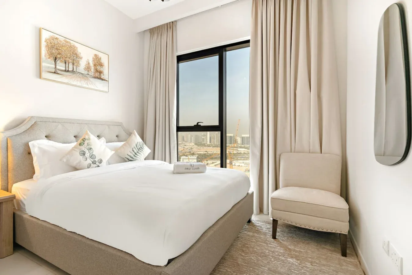A bright bedroom with a neatly made bed and a tall window.