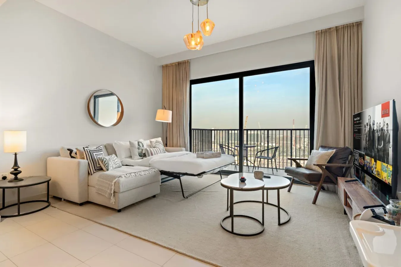 A bright living room with seating and large windows overlooking a balcony.
