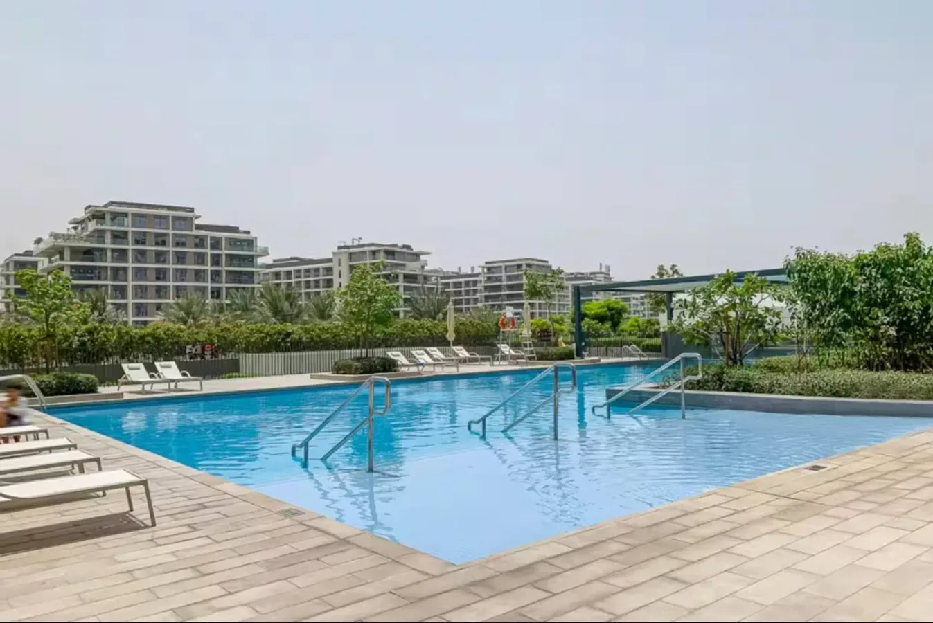 An outdoor swimming pool with steps and lounge seating on the surrounding deck.