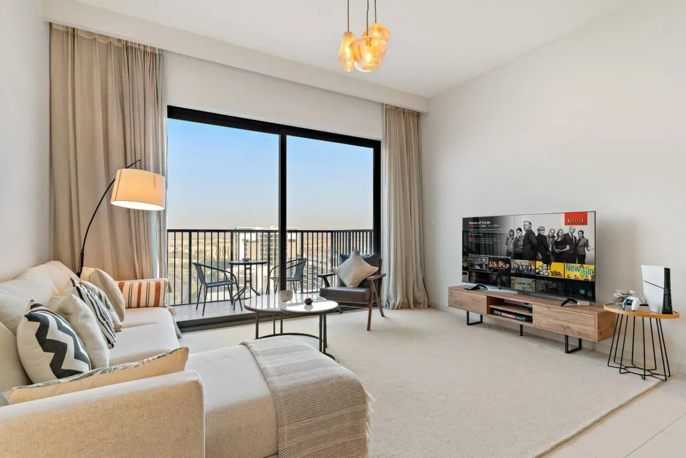 A bright living room with seating beside large windows opening onto a balcony.