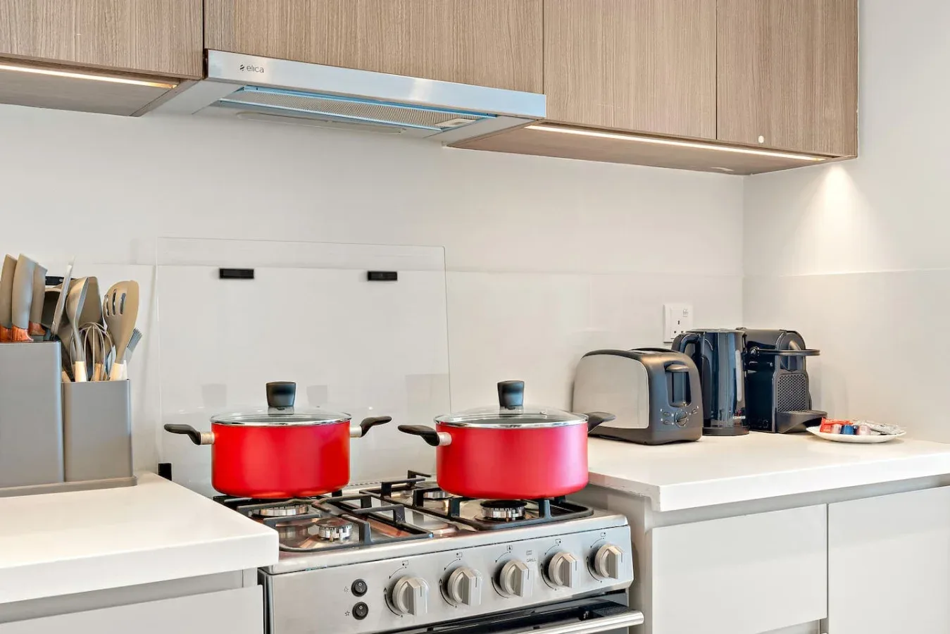 A kitchen with a stovetop, two pots, and countertop appliances.