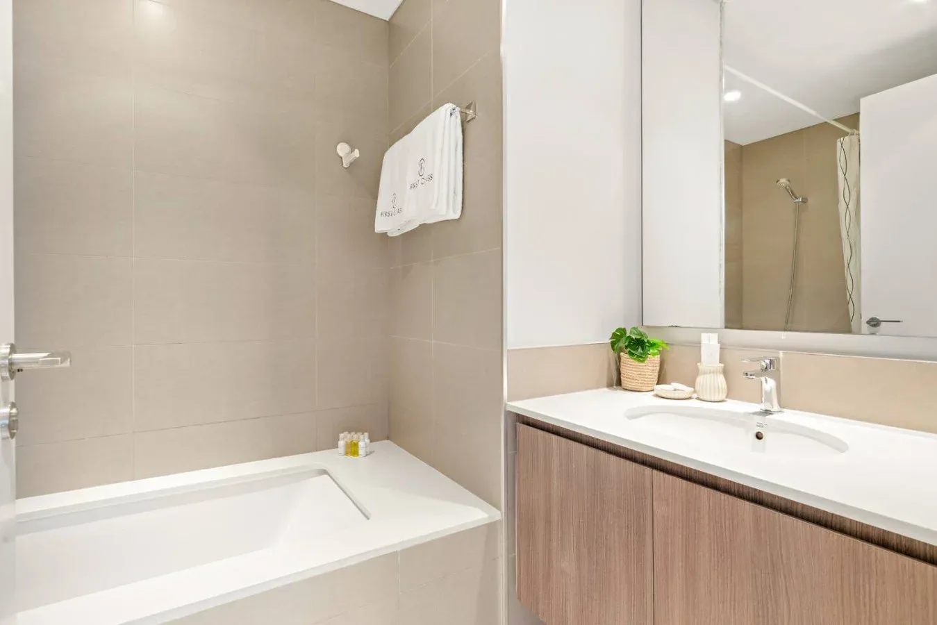 A bathroom with a bathtub, sink, and large wall mirror.