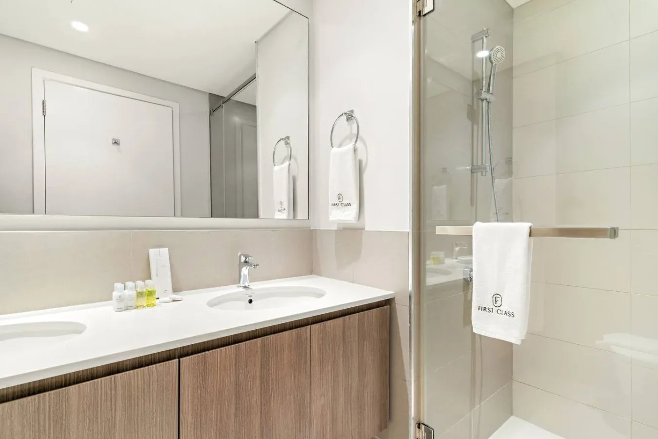 A bright bathroom with a long vanity and a glass shower.