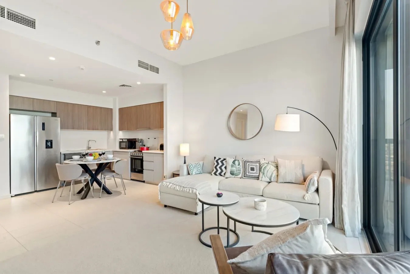 A bright open-plan living room and kitchen with seating and a dining table.