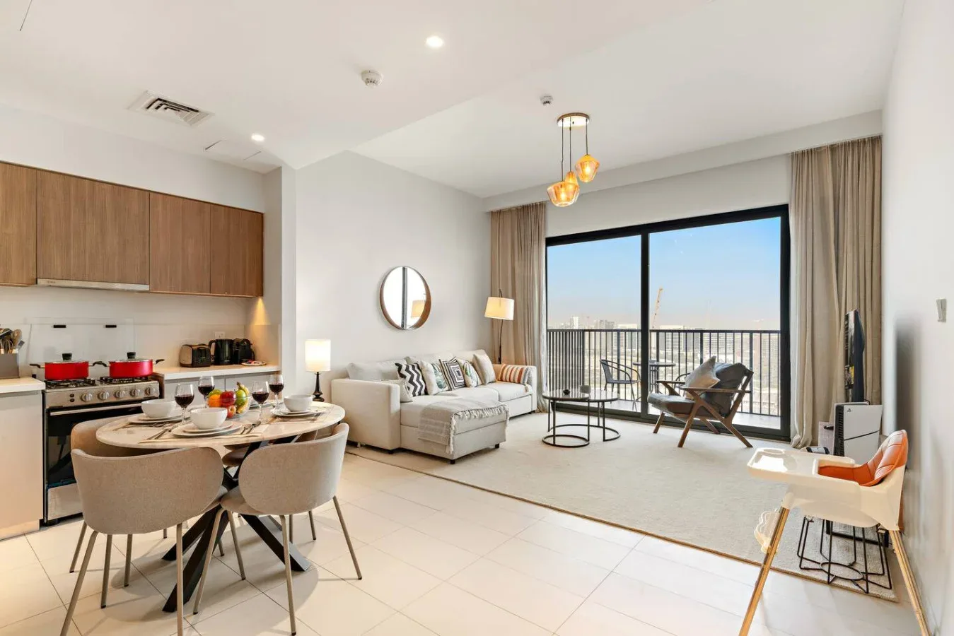 An open-plan living room and kitchen with a dining table beside the balcony doors.