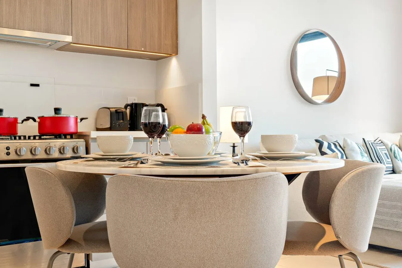 A dining area set for a meal sits beside a kitchen with a stove.