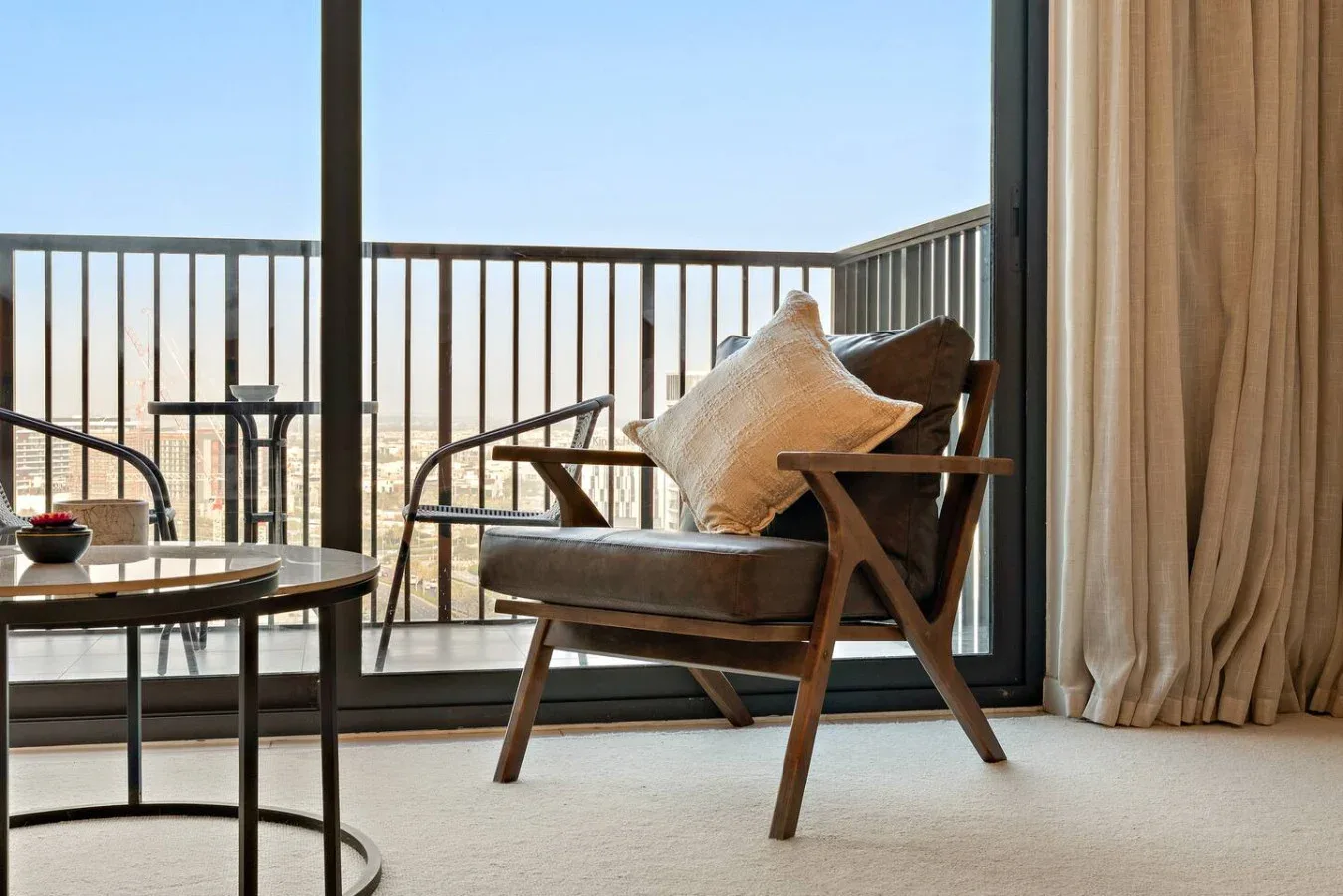 A balcony seating area with a cushioned chair beside a glass door.