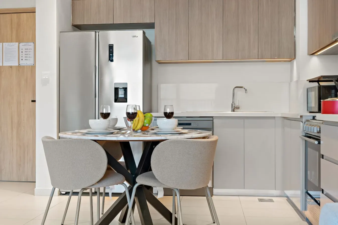 A dining area with a set table sits in front of a modern kitchen.