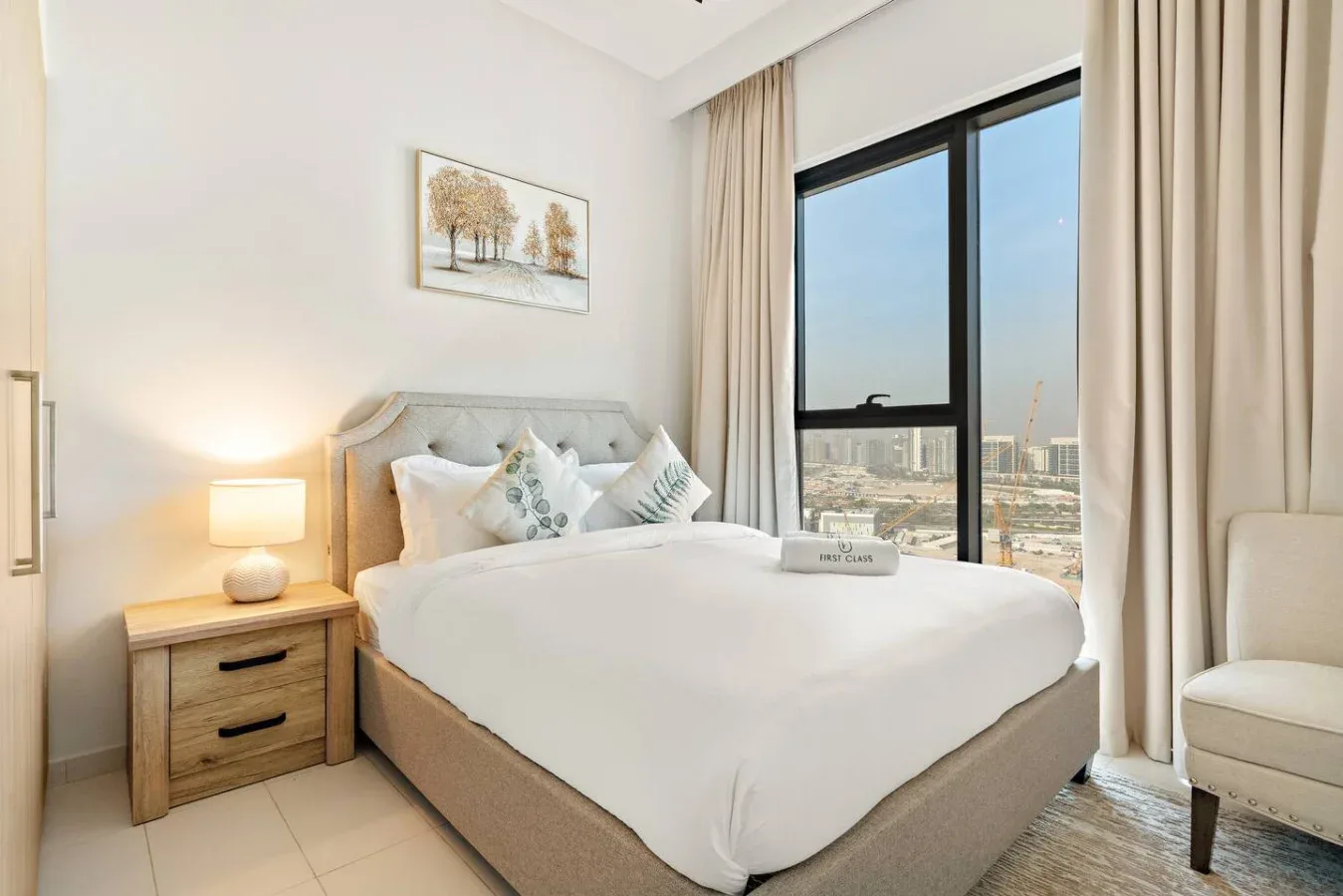 A bright bedroom with a neatly made bed beside a large window.