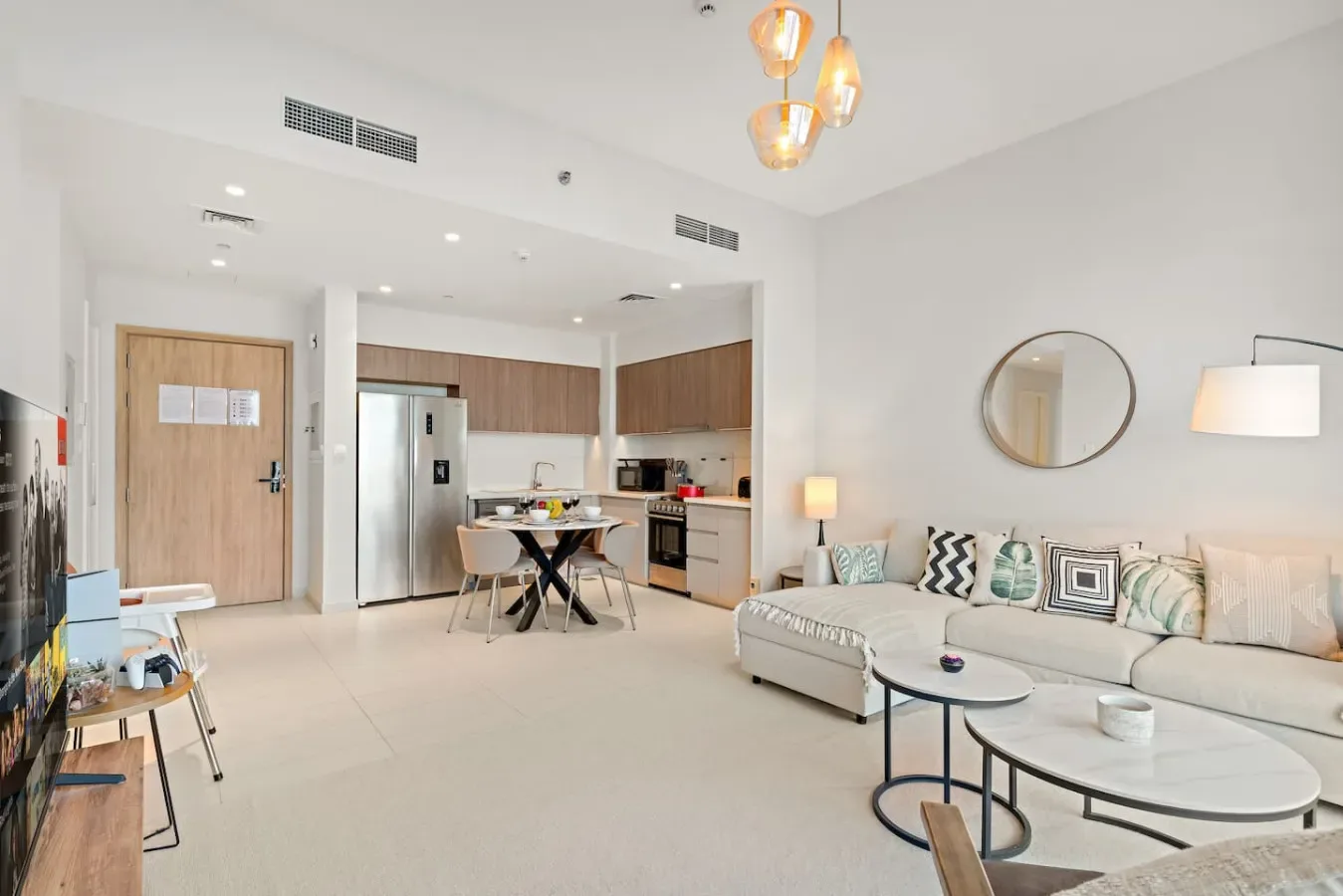 An open-plan living room and kitchen with a dining table and sectional seating.