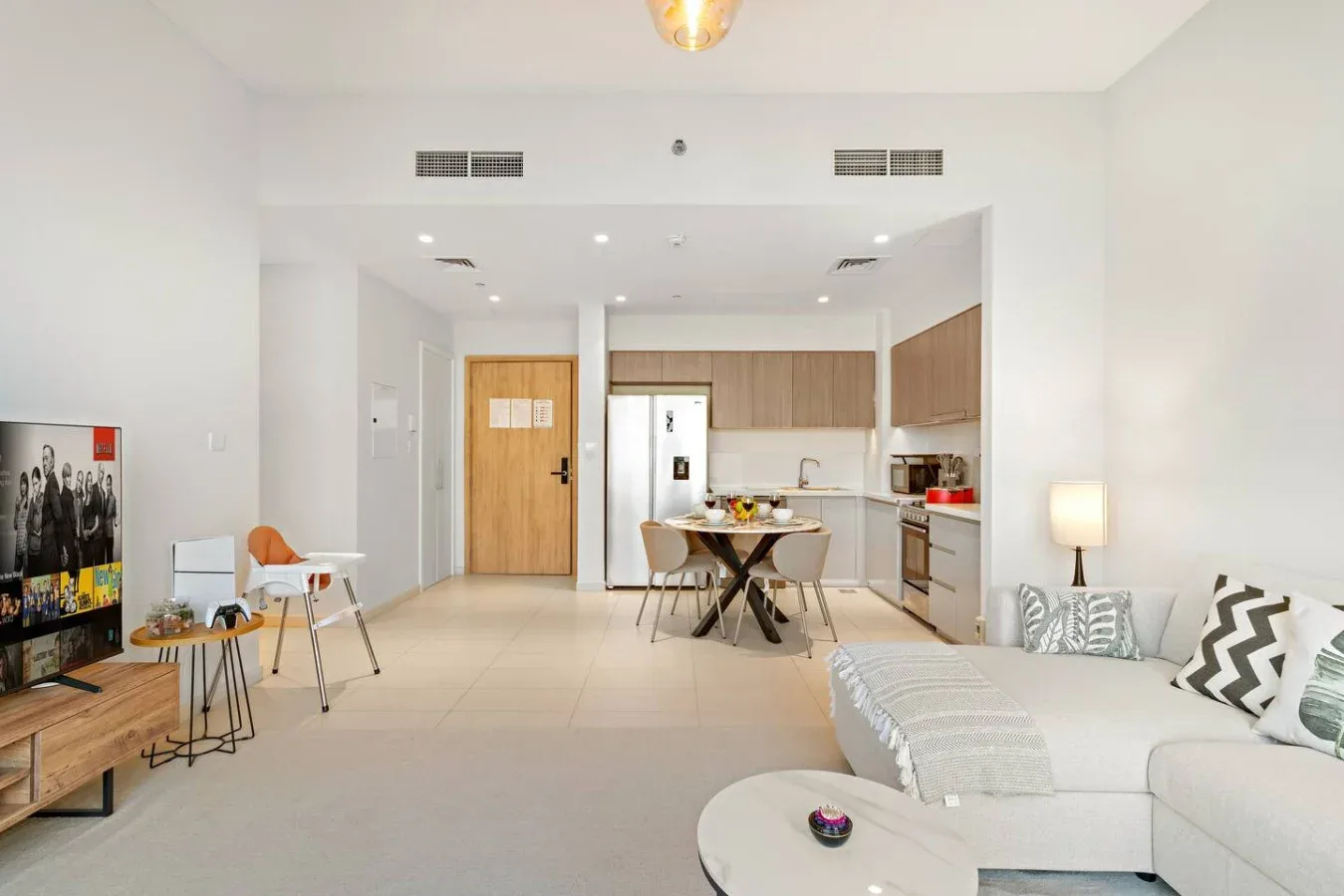 An open-plan living room and kitchen with a dining table between them.