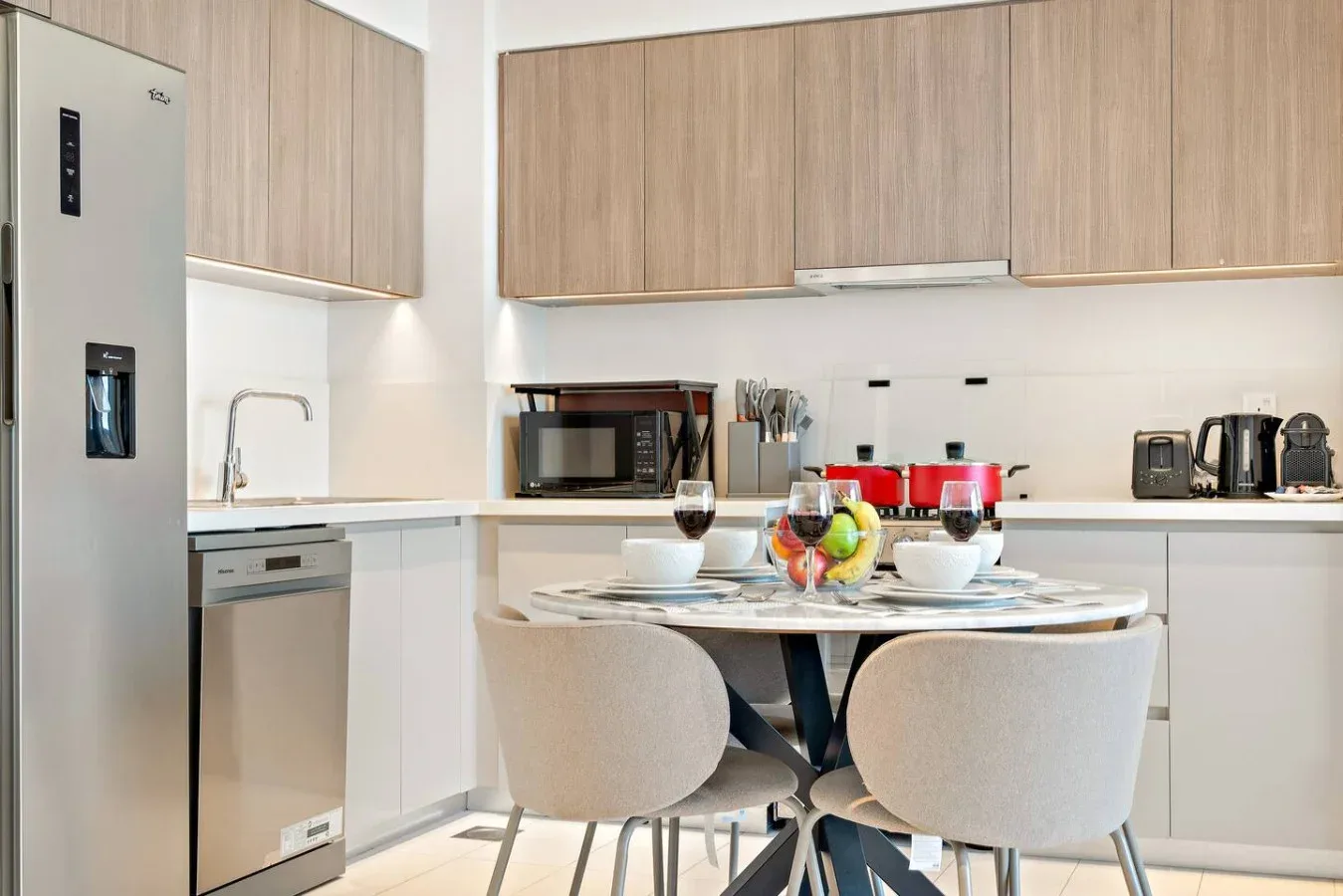 A modern kitchen with wood-toned cabinets and a dining table set with dishes.