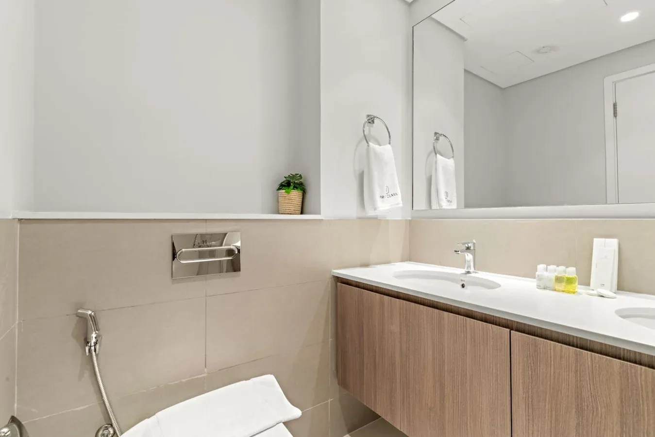 A modern bathroom with a wide vanity, large mirror, and wall-mounted towel holder.