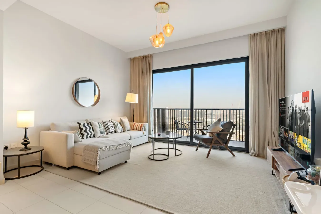 A bright living room with seating beside large windows opening onto a balcony.