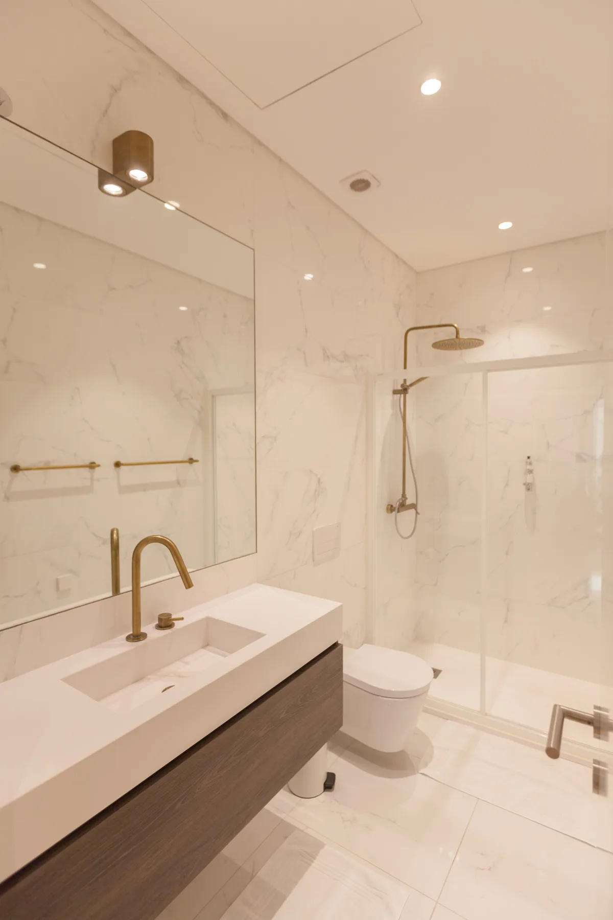 A bright bathroom with a sink, large mirror, and glass shower.