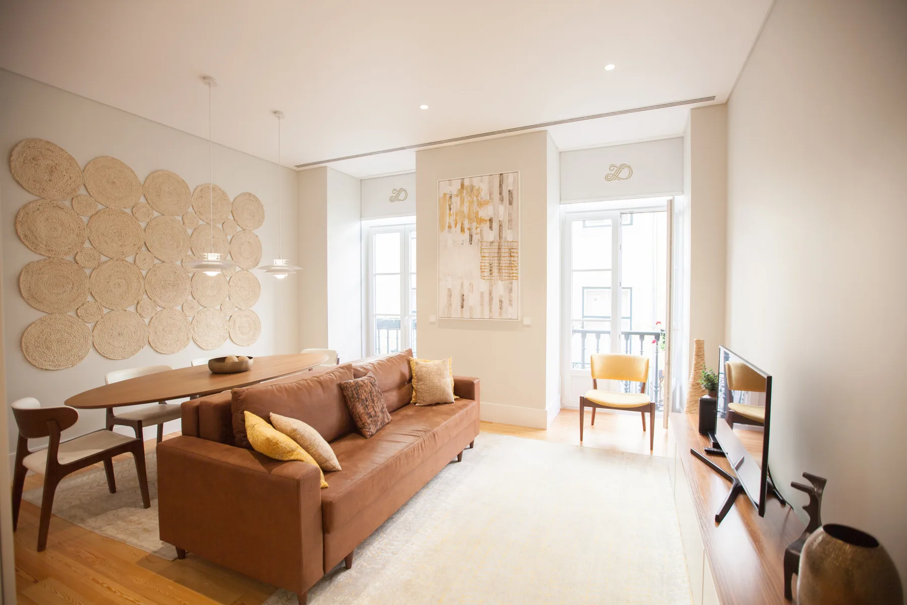 A bright living room with a sofa, dining table, and large windows.