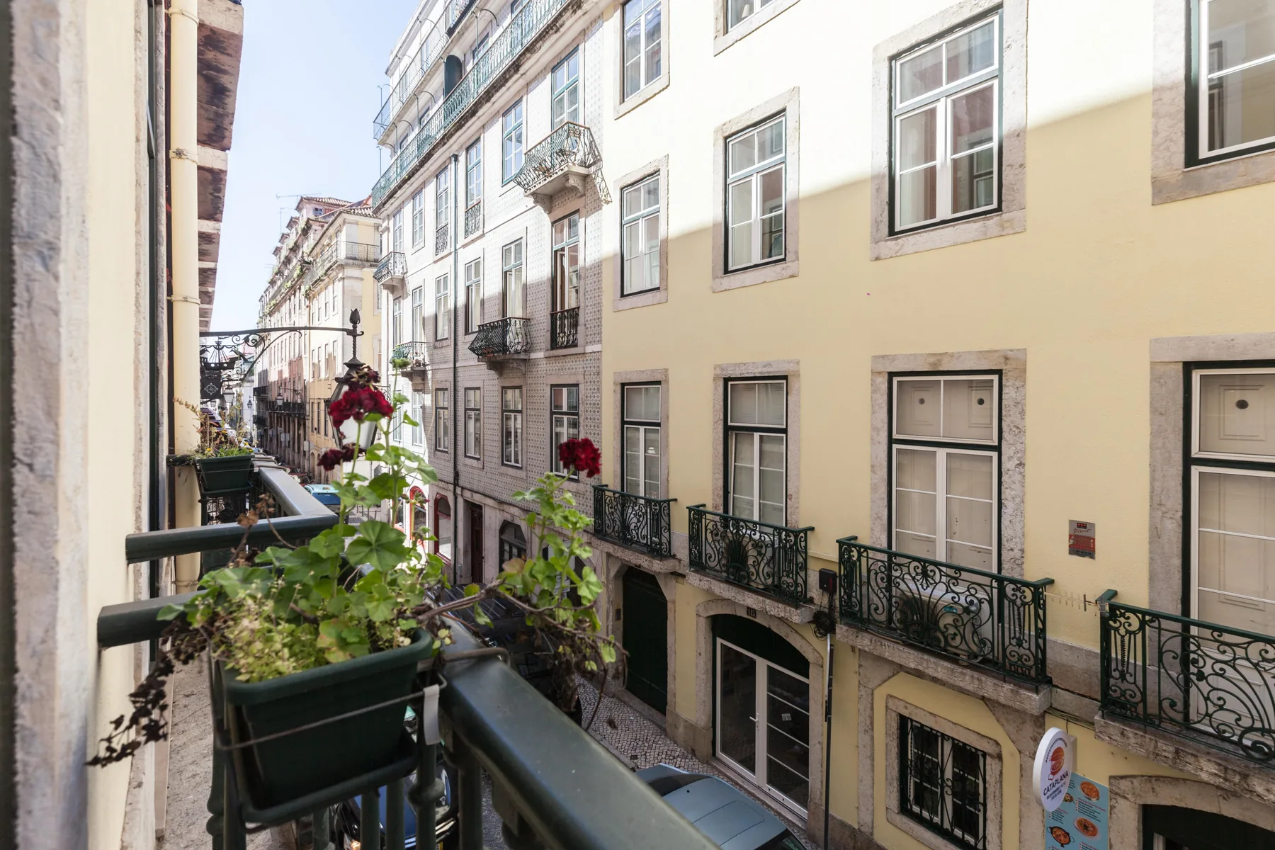 A balcony overlooks a narrow street lined with apartment buildings.