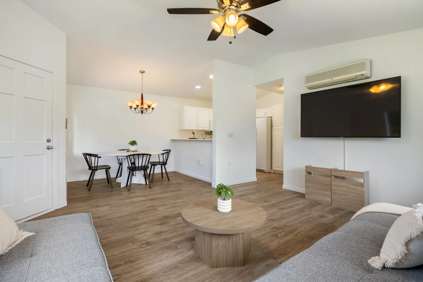 A living room with a wall-mounted television and a dining table in the background.
