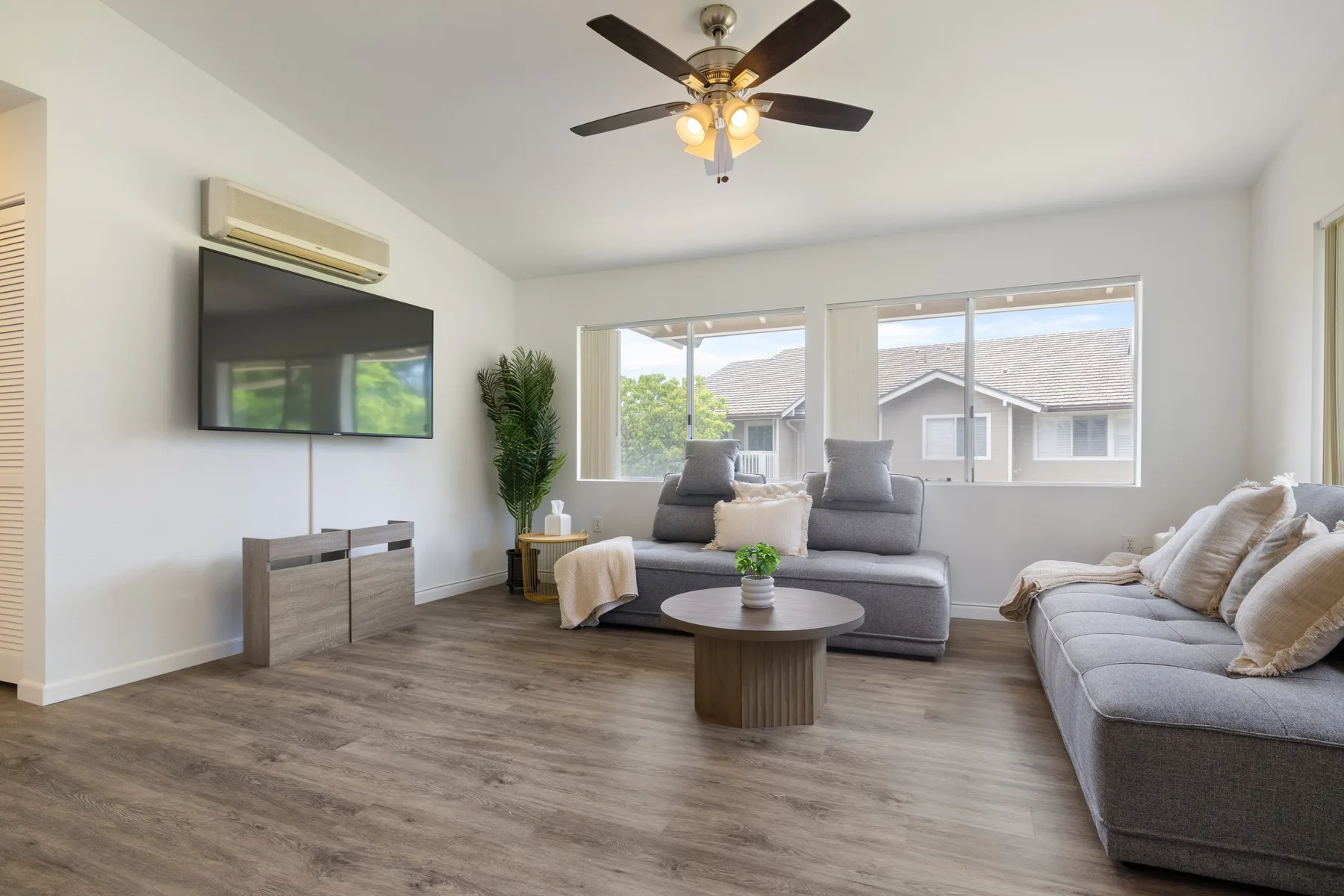 A bright living room with gray seating, a coffee table, and large windows.