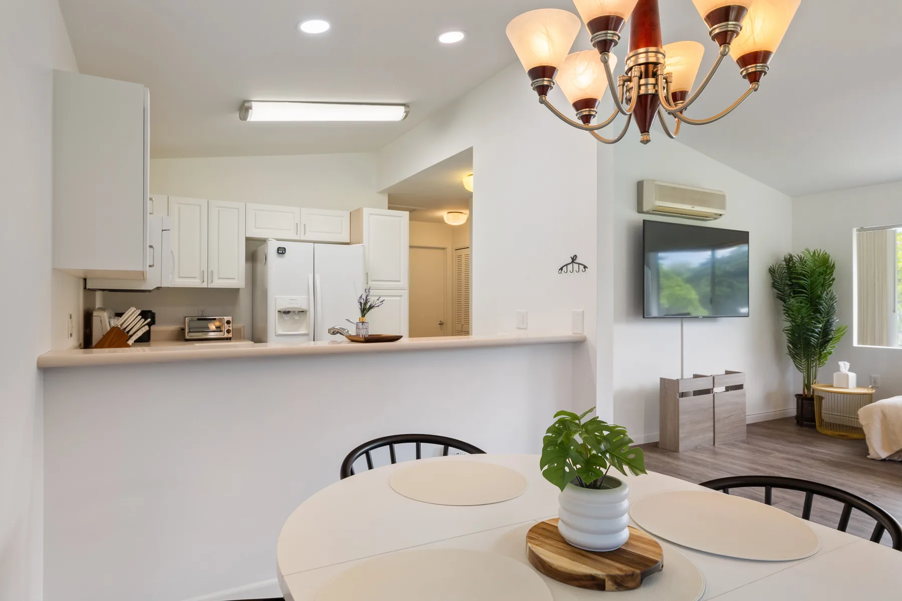 An open dining and kitchen area with a round table and white cabinetry.