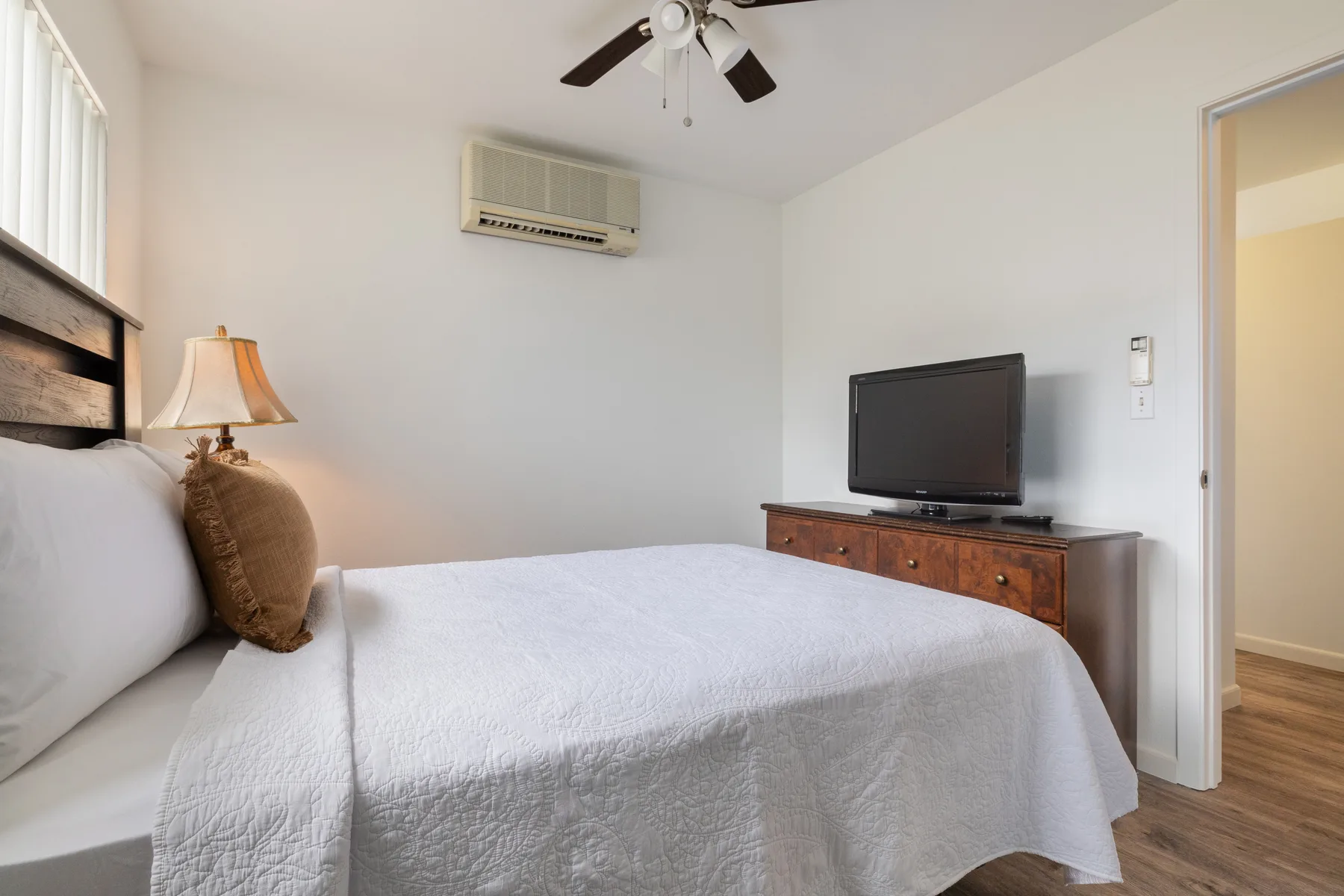 A bedroom with a neatly made bed and a television on a dresser.