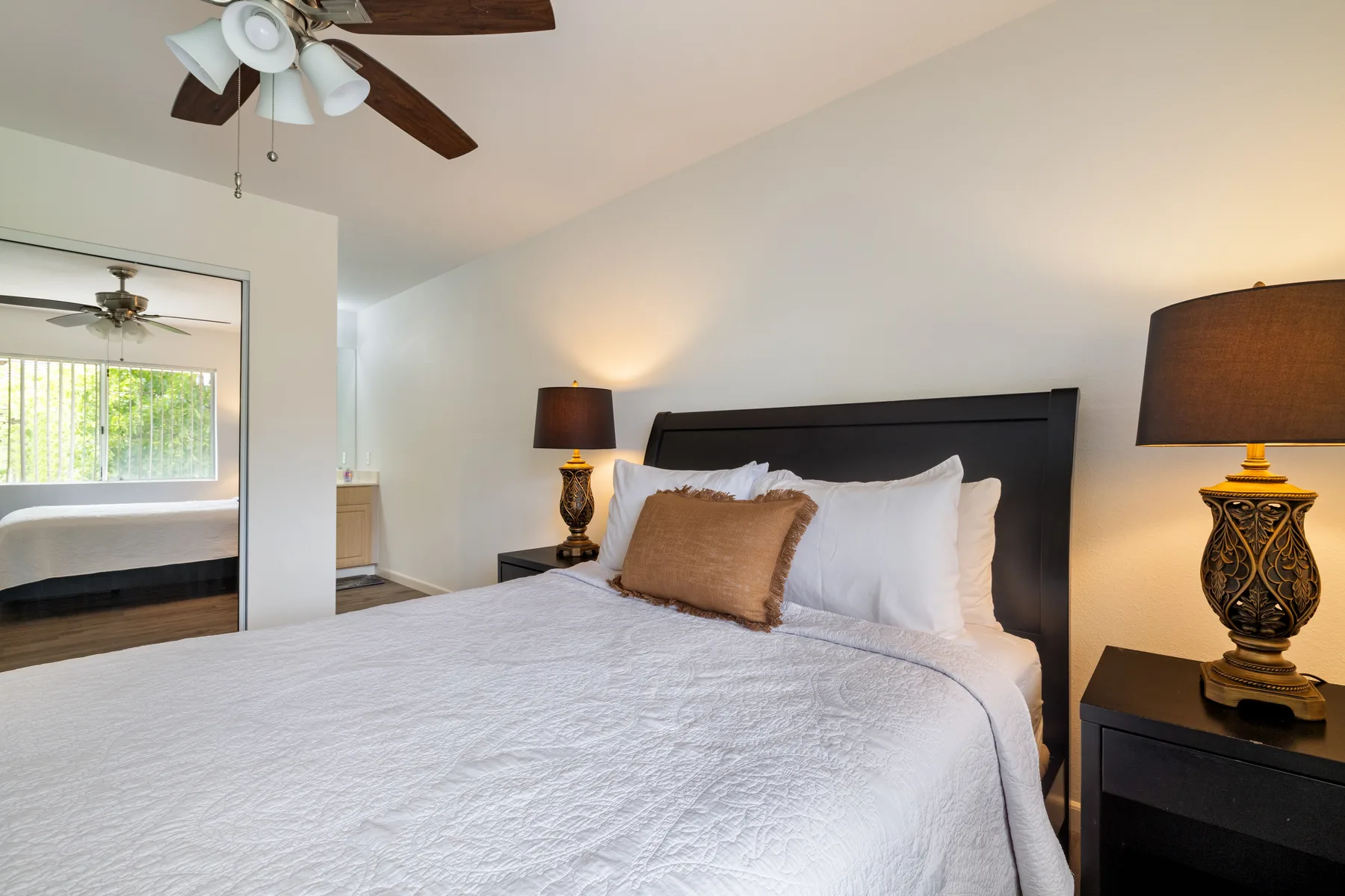 A bedroom with a large bed, bedside tables, and lamps.