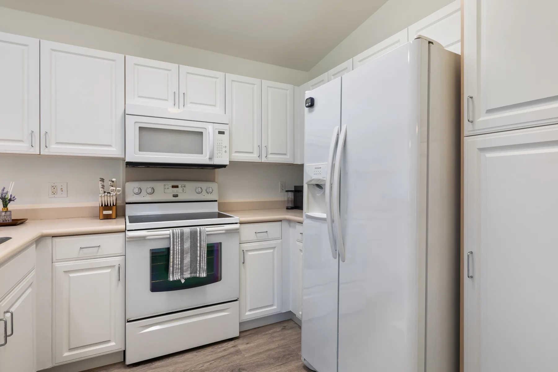 A bright kitchen with white cabinets, a stove, and a refrigerator.