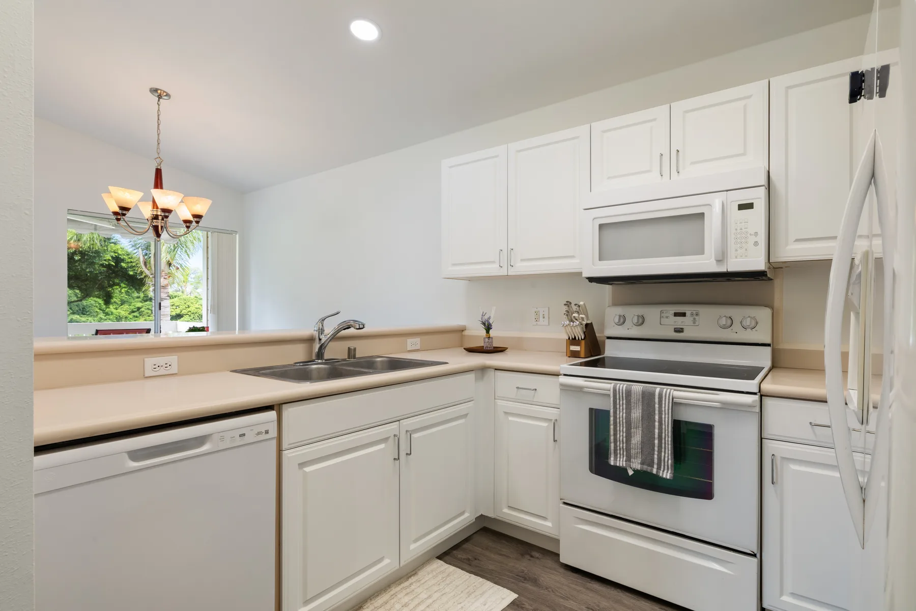 A bright kitchen with white cabinets, a sink, and stainless steel appliances.