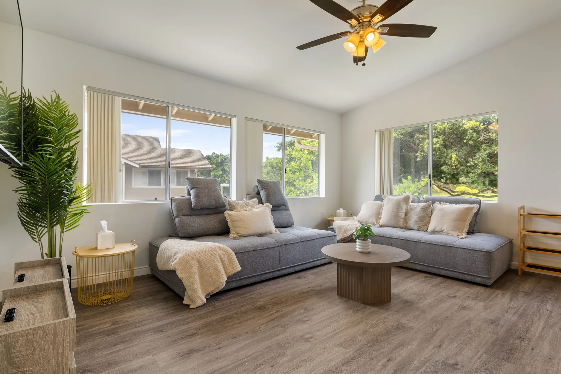 A bright living room with a gray sectional sofa and a round coffee table.
