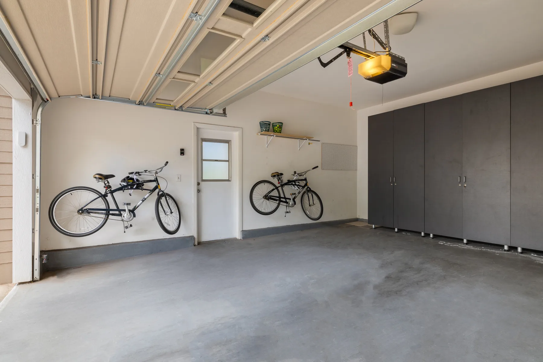 A garage interior with bicycles mounted on the walls and storage cabinets.