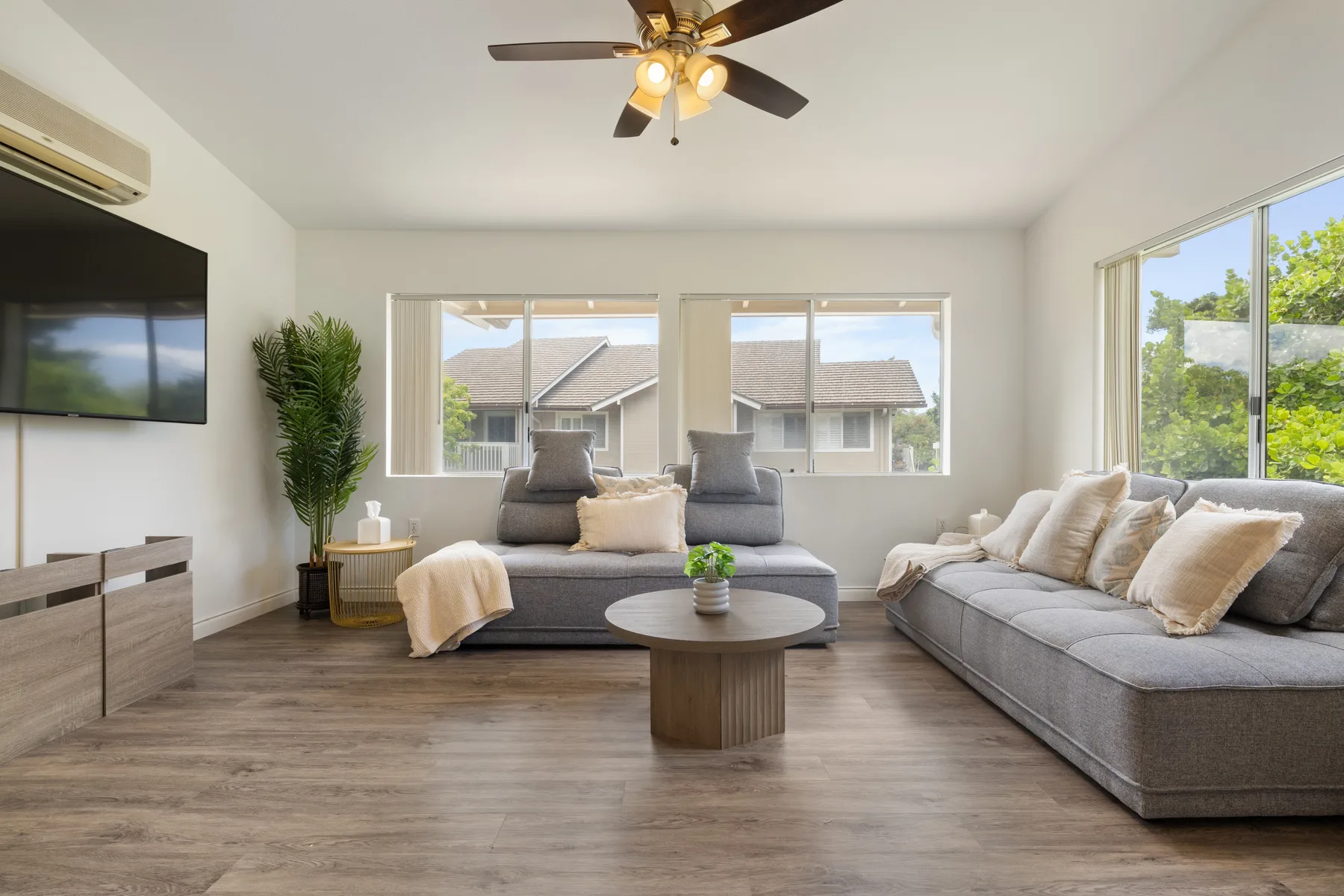 A bright living room with gray seating, a coffee table, and large windows.