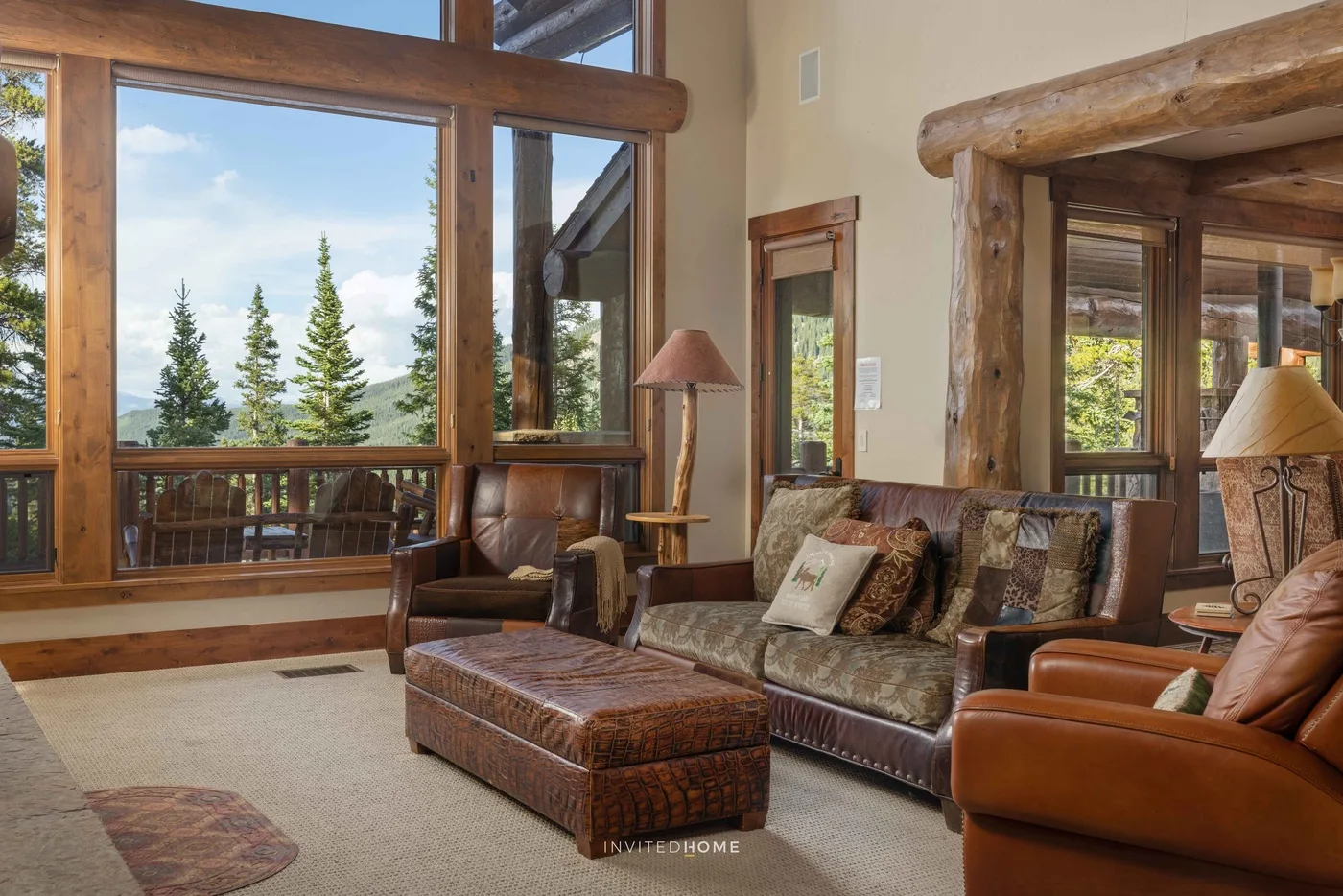 Una sala de estar con asientos y grandes ventanas con vista a árboles.