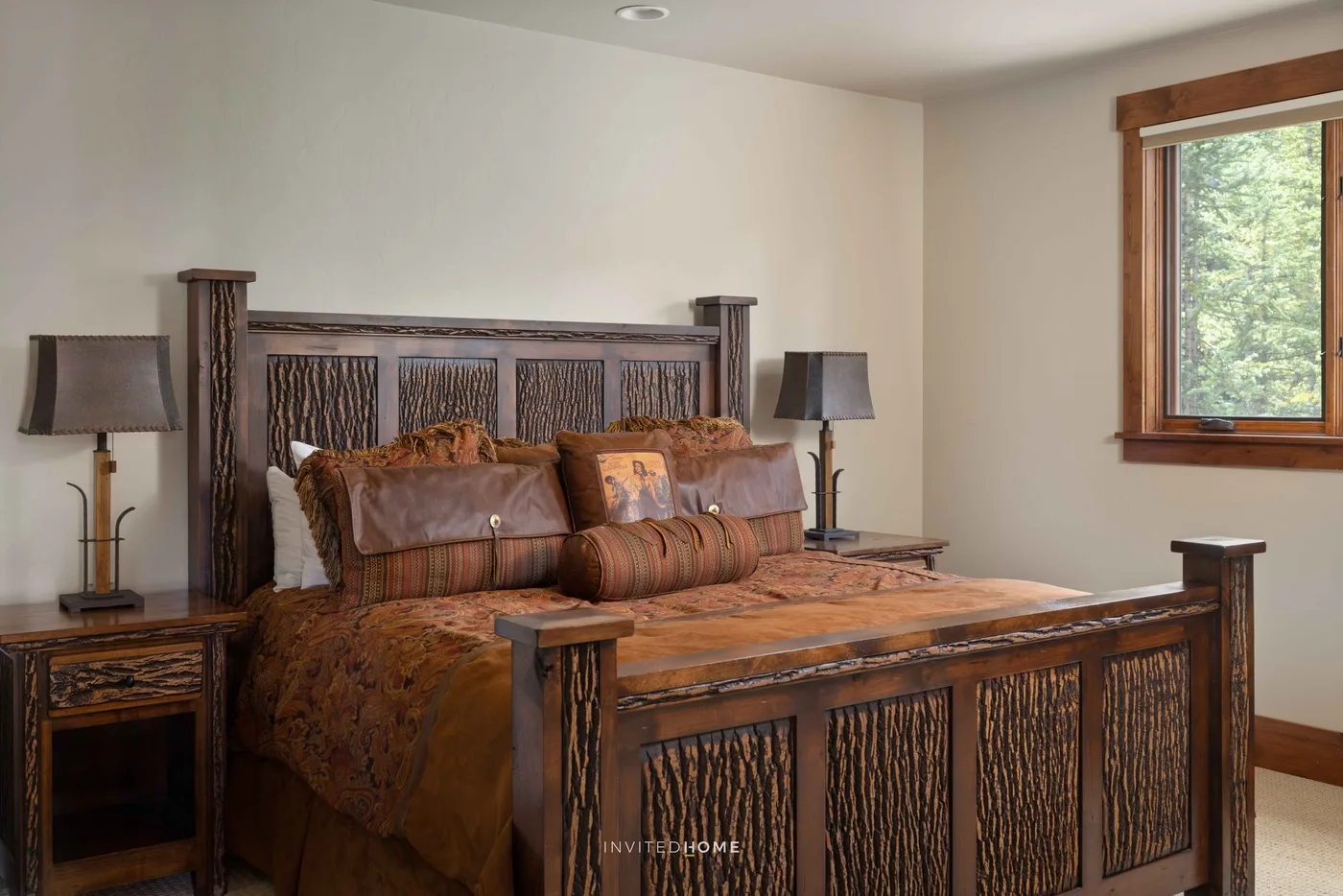 Un dormitorio con una cama de madera tallada y una ventana con vista a los árboles.