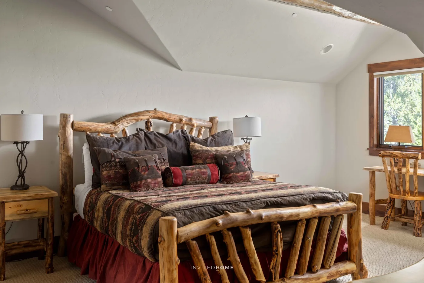 Dormitorio con cama de troncos, ropa de cama estampada y lámparas de noche.