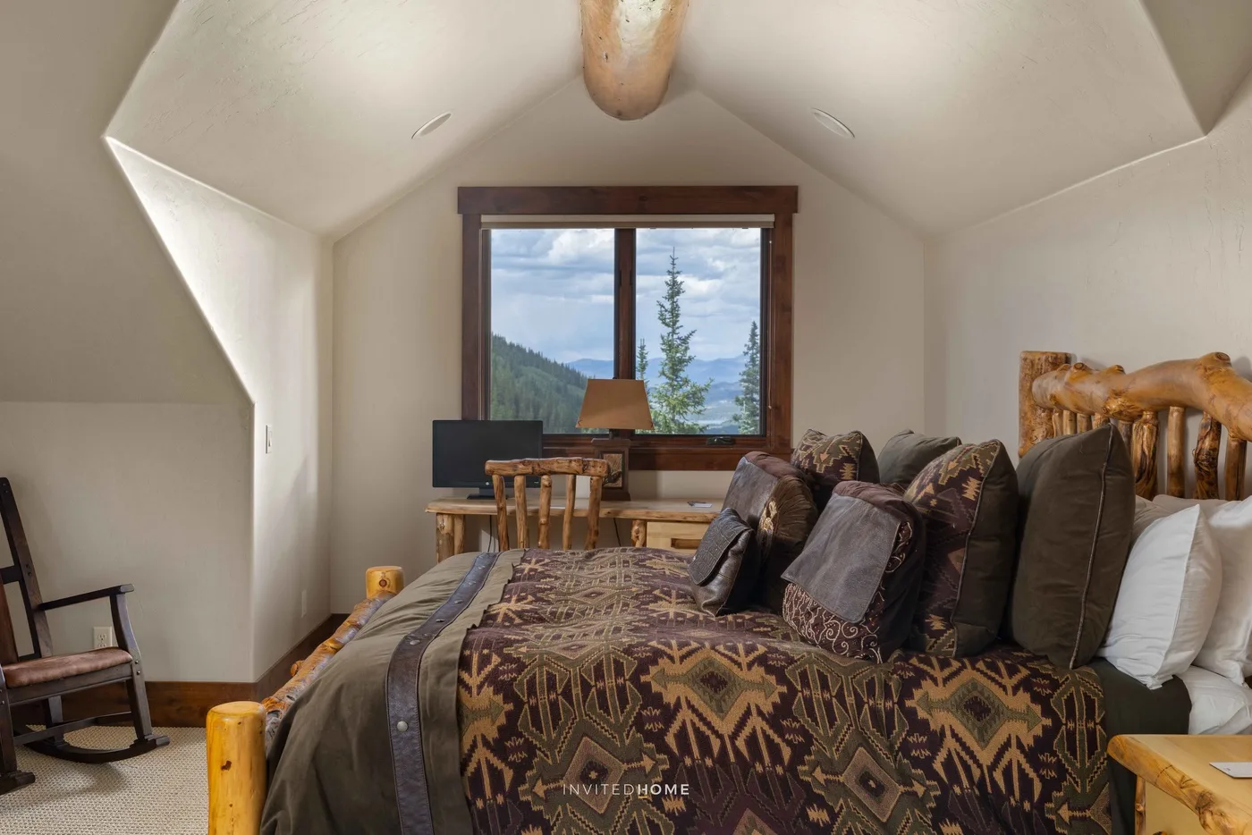 Un dormitorio con una cama grande y una ventana con vistas a una ladera boscosa.