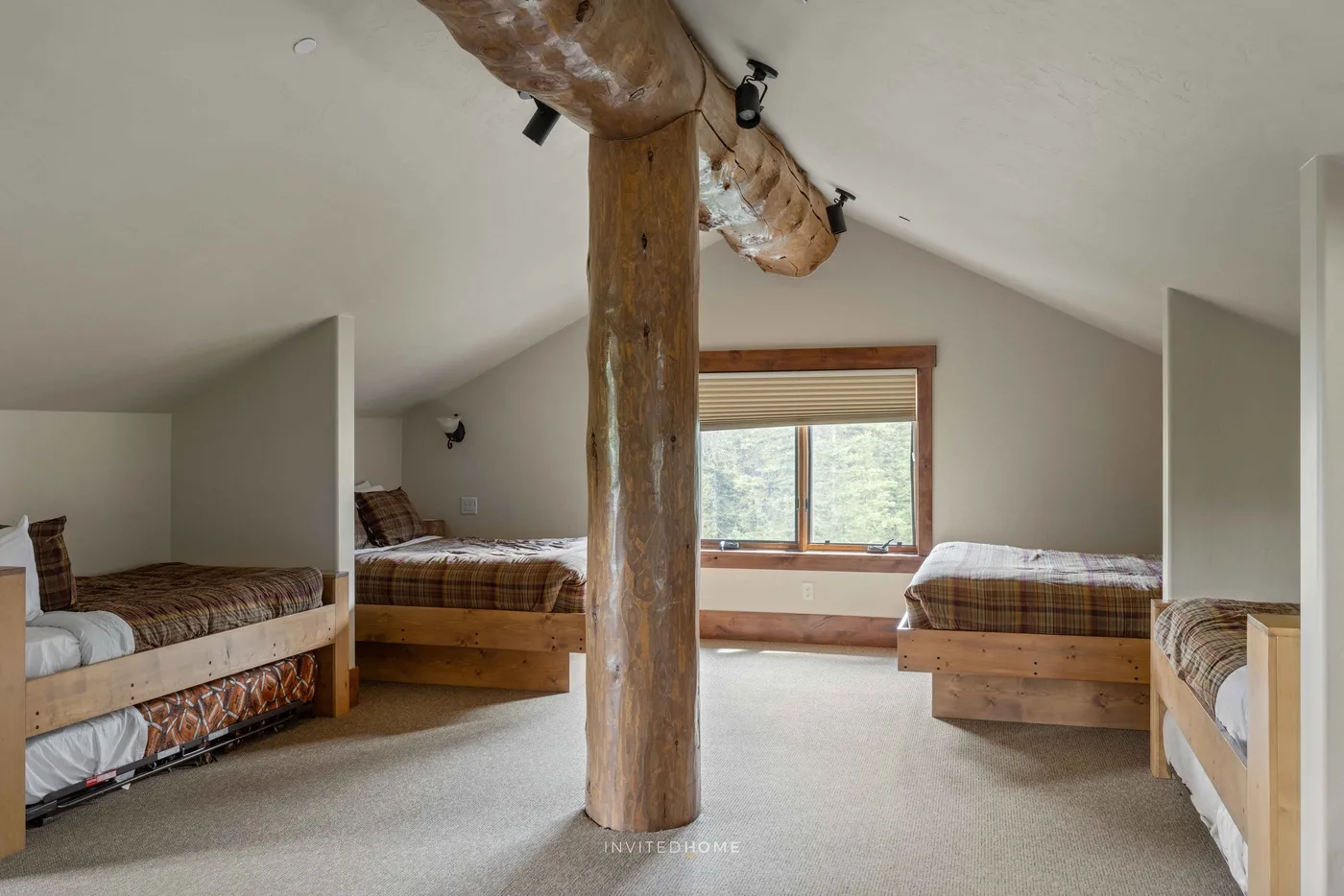 Un dormitorio tipo loft con varias camas y una ventana con vista a los árboles.