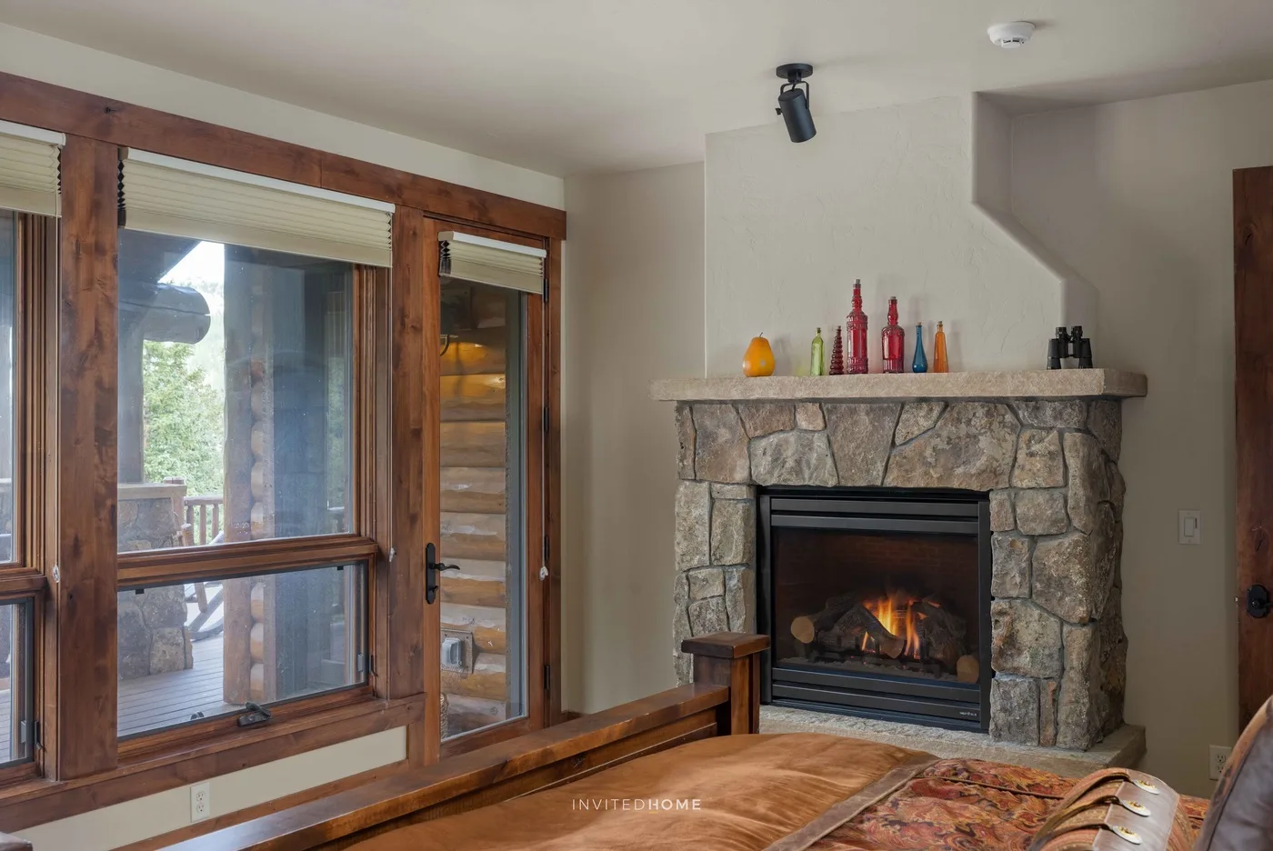 Una sala de estar con una chimenea de piedra y ventanas con marcos de madera.