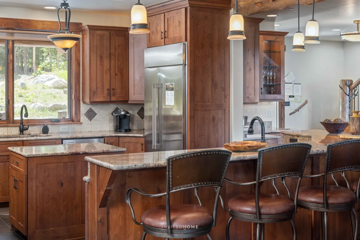 Una cocina amplia con gabinetes de madera, encimeras de piedra y una isla central.