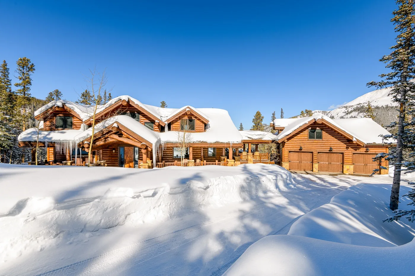 Un gran albergue de madera se alza tras la nieve profunda, con árboles de hoja perenne cerca.