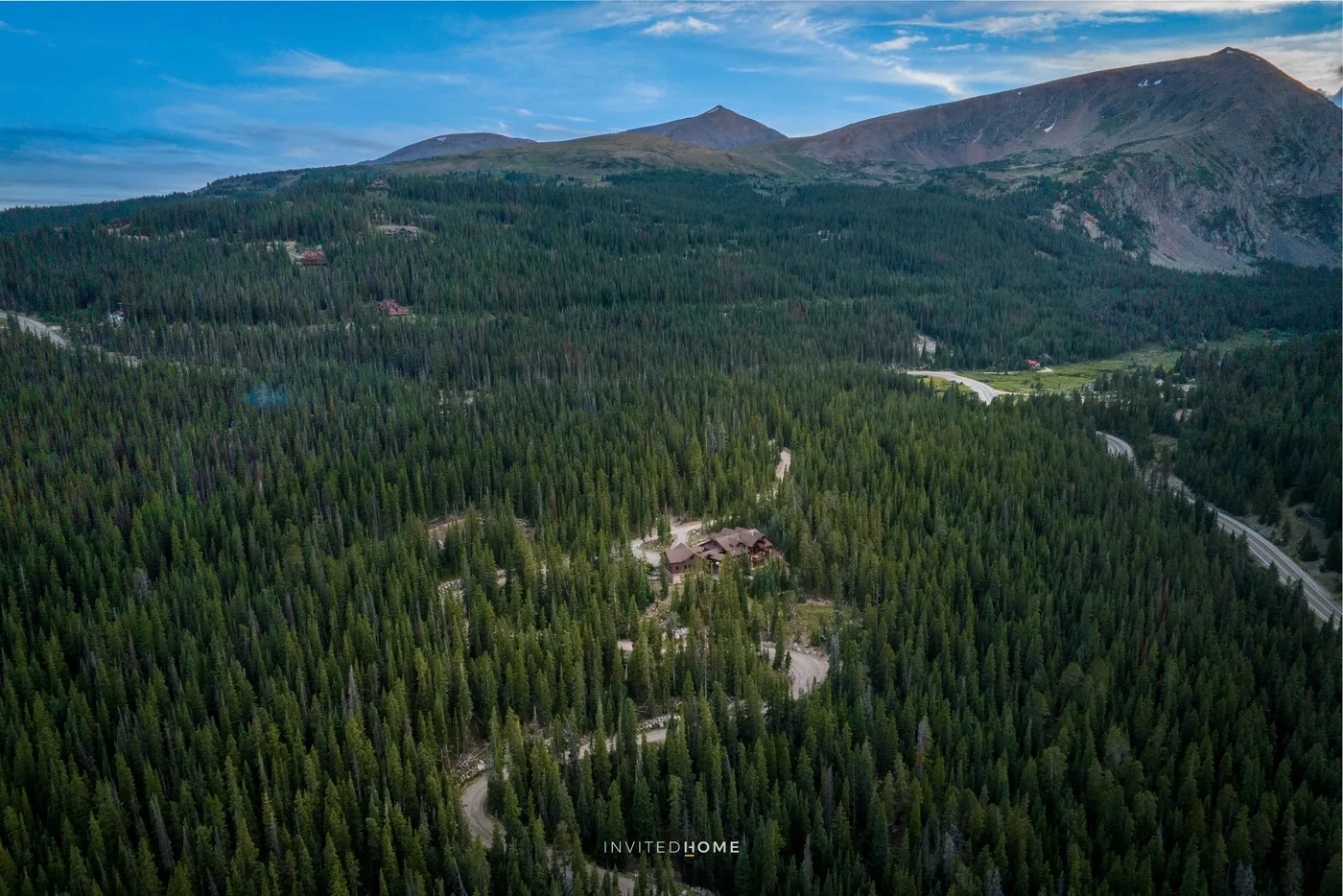 Vista aérea de un paisaje montañoso cubierto de bosque bajo un cielo parcialmente nublado.
