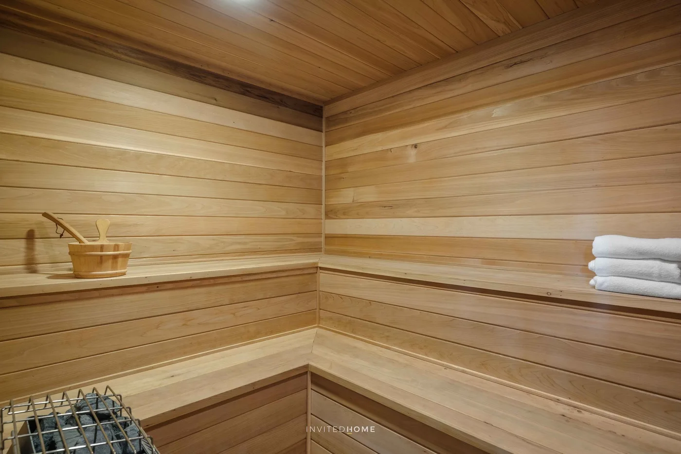 Una sauna revestida de madera con bancos escalonados y toallas dobladas.