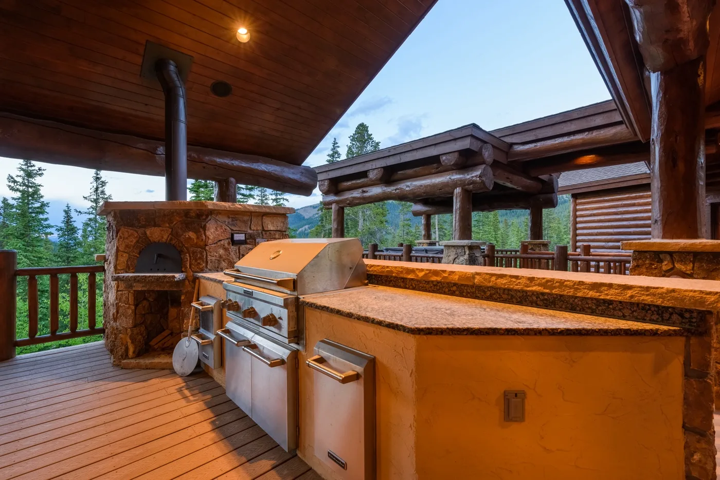 Una cocina exterior cubierta con parrilla empotrada y encimera de piedra.
